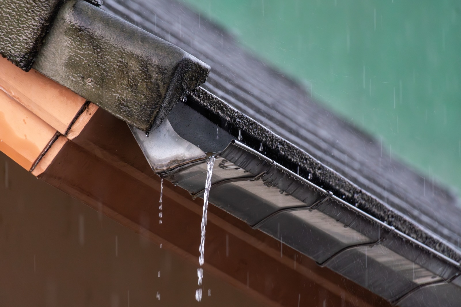 Regenwater stroomt over een verstopte dakgoot