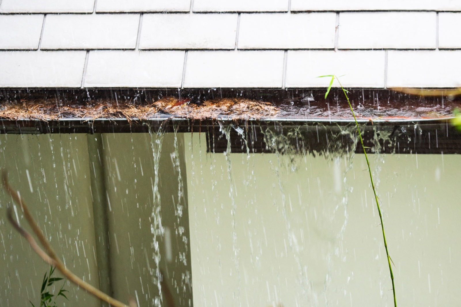 Verstopte regenpijp zorgt voor overlopende dakgoot tijdens hevige regen